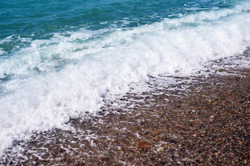 Sea wave on a pebble beach close up 