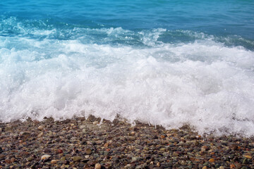 Sea wave on a pebble beach close up 