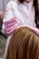 Fototapeta premium Doctor apply serum on female head, vitamins in woman skin head for hair growth and against dandruff in cosmetology clinic, closeup view. Hairs cure. Trichology in medicine.