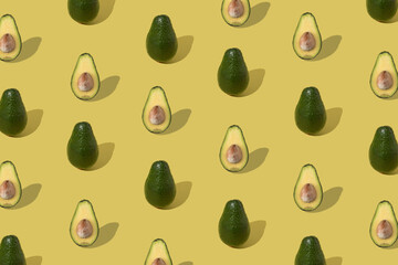 Creative design of a pattern with green avocados photographed on yellow background. Minimal concept