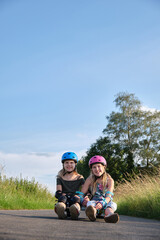 identical twin sisters having fun with their scateboards on a sunny summer day. Two active girls and their hobby.