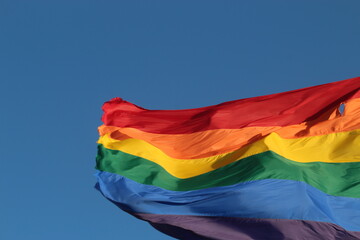 Pride flag flying against blue sky