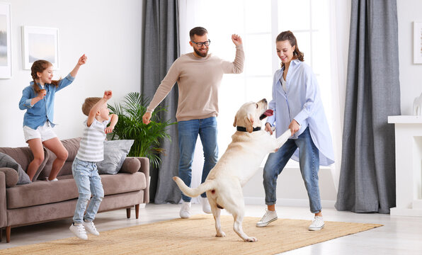 Cheerful family with kids and dog dancing at home
