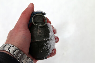 Hand grenade in hand on a background of snow