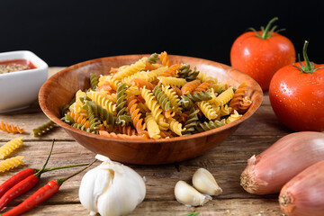 Italian pasta preparation on wooden background, tomatoes, garlic, onions, herbs