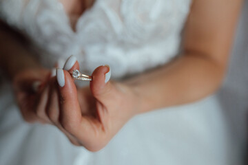 Obraz na płótnie Canvas the bride holds a gold wedding ring with a diamond