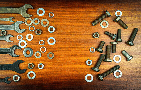 Different Wrenches, Bolts, Nuts And Washers On A Brown Wood Texture Background