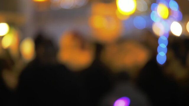 Abstract image background with anonymous city crowd and colorful Christmas lights, busy urban scenery, unrecognizable people walking, slow motion evening shot