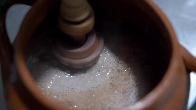 Shaking hot cocoa in a clay pot with Mexican molinillo