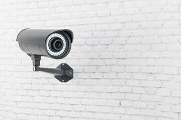 Modern black security camera installed on light brick wall