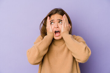 Young skinny caucasian girl teenager on purple background covering ears with hands trying not to hear too loud sound.