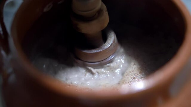 Shaking hot cocoa in a clay pot with Mexican molinillo