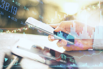 Forex trading concept with digital tablet and smartphone in man hand and business charts with financial graphs. Double exposure