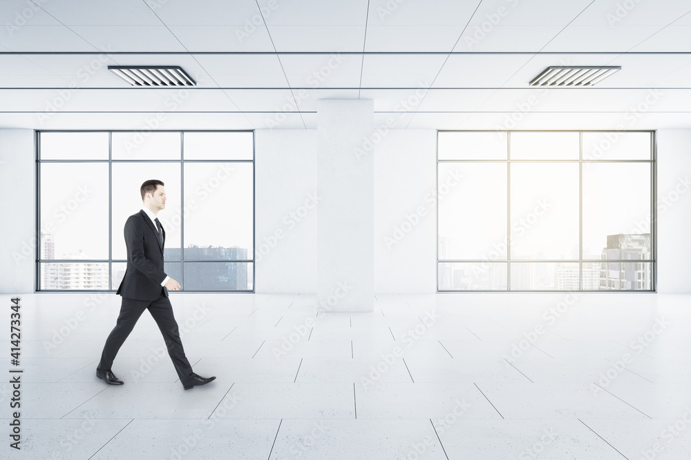Poster businessman in motion in light empty spacious hall room with windows and city view