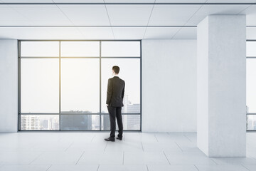 Businessman looking out the window from modern room with light interior design