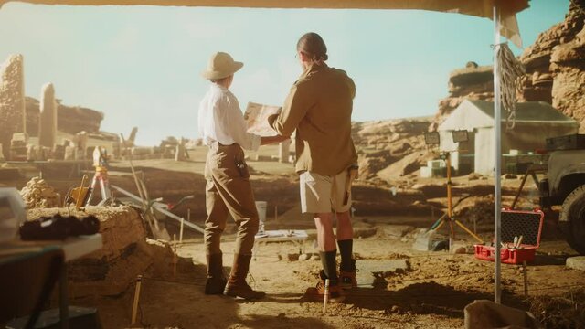 Archaeological Digging Site: Two Great Archeologists Work on Excavation Site, Look around, Use Map to Inspect Newly Discovered Ancient Civilization Architectural Site, Planning Work. Panoramic Shot