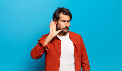 young handsome indian man looking serious and curious, listening, trying to hear a secret...