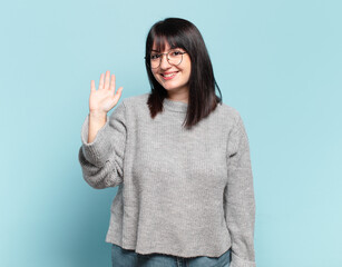 plus size pretty woman smiling happily and cheerfully, waving hand, welcoming and greeting you, or...