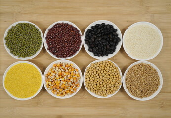 Various beans and grains in bowls on wooden background, top view, rich in nutrients, healthy eating