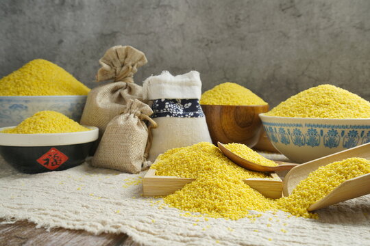 Raw millet in various containers, old wall background, healthy food