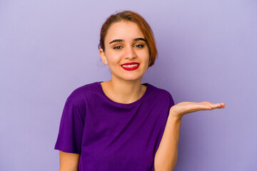 Young arab mixed race woman showing a copy space on a palm and holding another hand on waist.