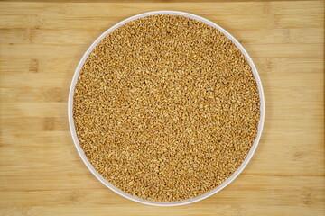 Top view of harvested ripe wheat on a round porcelain plate on wooden table