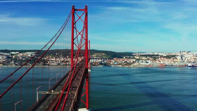 Aerial footage of the 25 De April Bridge. Drone flying over red bridge connecting Lisbon city and Almada, Portugal. Tagus river.