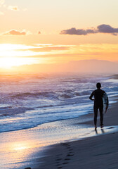 Surfer on the beach running during the sunset