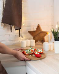 Girl's hands put wooden dish stuffed with cheese and pepper on the table top
