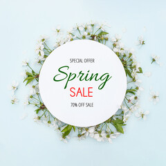 Text Spring Sale. Special offer. 70% off. Round frame with spring flowers. Flowers on cherry tree branches in form of wreath on blue background. Leaf pattern. Flat lay, top view, copy space. Mockup