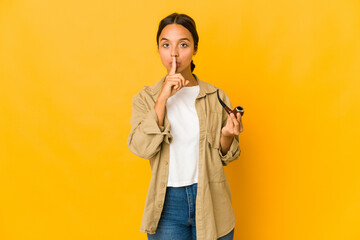 Young hispanic woman holding a smoking pipe keeping a secret or asking for silence.