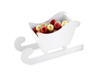 Many Christmas balls in toy wooden sleigh on white background