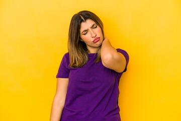 Young indian woman isolated on yellow background having a neck pain due to stress, massaging and touching it with hand.