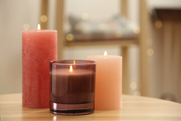 Obraz na płótnie Canvas Stylish burning candles on wooden table indoors