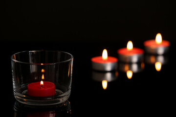 Wax candles burning on table in darkness. Space for text