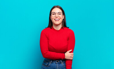 young pretty casual woman laughing shyly and cheerfully, with a friendly and positive but insecure...