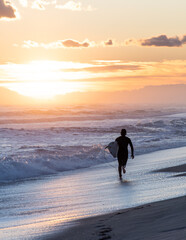Surfer on the beach running during the sunset
