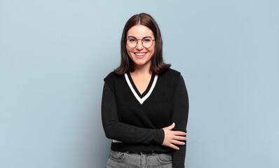 young pretty casual woman laughing shyly and cheerfully, with a friendly and positive but insecure...