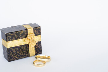 Wedding Rings and Little Jewelery Box. mall cardboard box decorated with gold ribbons and a pair of gold wedding rings
