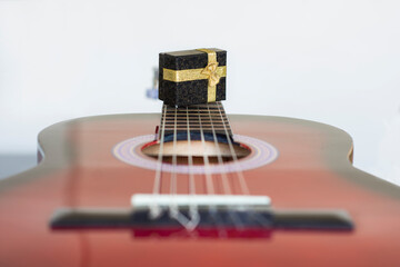 Box and Guitar. cardboard jewelry box with gold color ribbons above guitar strings