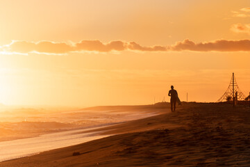 Fototapeta na wymiar Surfer on the beach running during the sunset