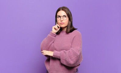 young pretty casual woman with a concentrated look, wondering with a doubtful expression, looking...