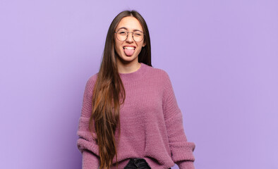 young pretty casual woman with cheerful, carefree, rebellious attitude, joking and sticking tongue...