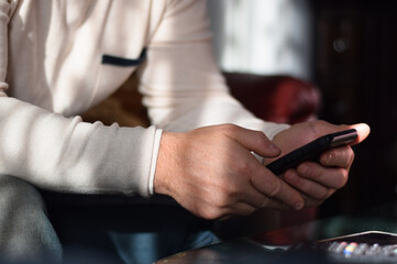 Man is sitting on a couch using mobile phone
