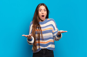 young pretty casual woman feeling extremely shocked and surprised, anxious and panicking, with a...