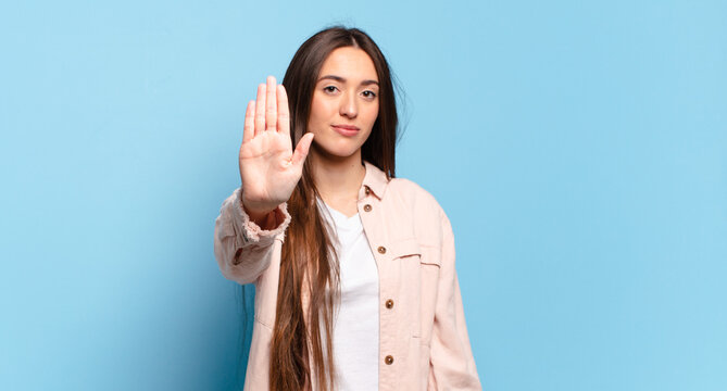 young pretty casual woman looking serious, stern, displeased and angry showing open palm making stop gesture