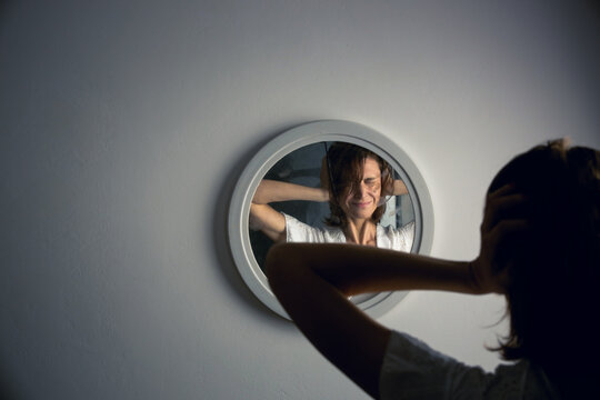 Reflection of a woman's face in broken mirror. Depression, anxiety, phobia, suicide and mental health concept.
