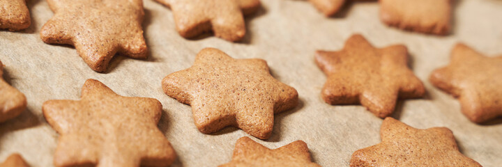 Star cookies on tray. Woman baked christmas biscuit. Many pieces of cake at paper. Holiday sweet food. Process prepare. Lot cinnamon desserts