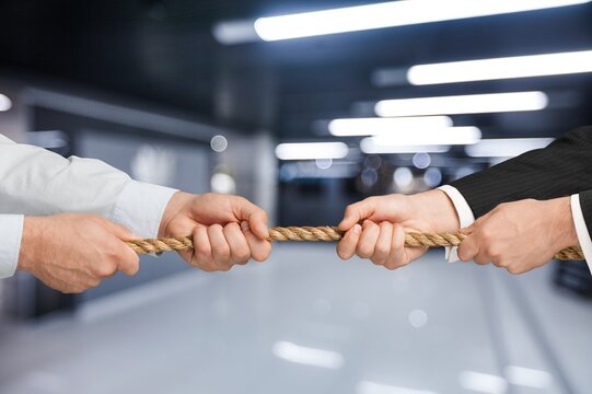 Business people pulling rope in opposite directions at office