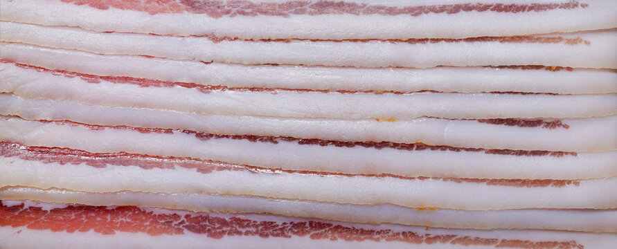 Pancetta. .Close up of Italian pancetta cut into slices..A Pork meat salumi..Cured meat products. .Food background. Close up..Panoramic macro image. Hi-res banner.